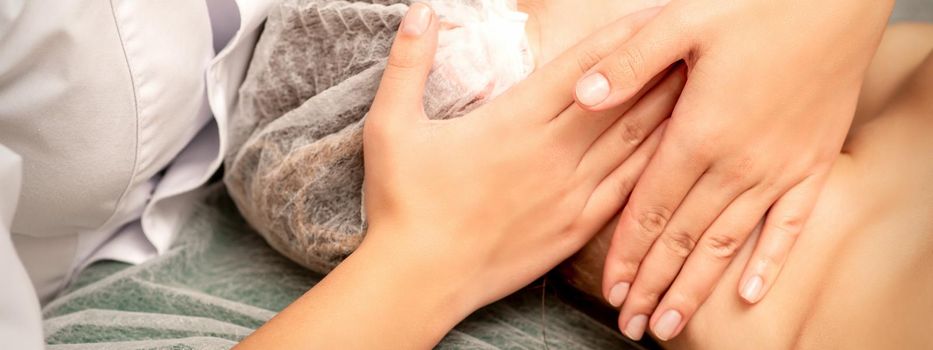 Facial massage. Hands of a masseur massaging neck of a young caucasian woman in a spa salon, the concept of health massage