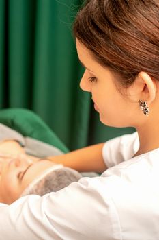 Massaging female breast, and shoulder. Beautician doing chest and shoulders massage of the young beautiful caucasian woman in beauty spa salon