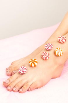 Depilation, waxing concept. Round candies lying down in a row on the female leg, close up
