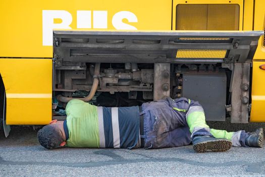 Mechanic working on a broken down bus with engine visible