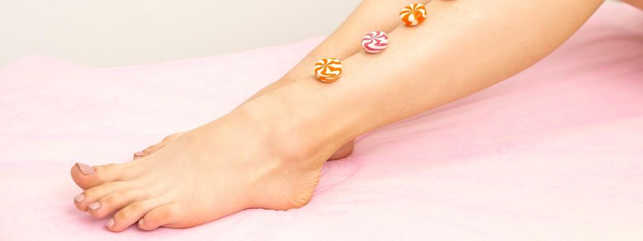 Depilation, waxing concept. Round candies lying down in a row on the female leg, close up