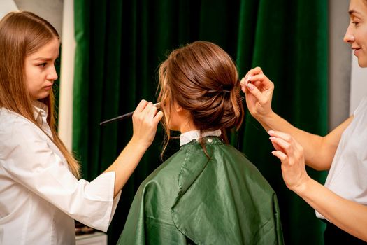 Makeup artist and hairdresser prepare the bride making hairstyle and makeup in a beauty salon