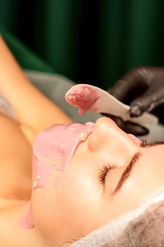 Beautiful young caucasian woman receiving an alginic mask to the face in beauty salon. Facial skin treatment