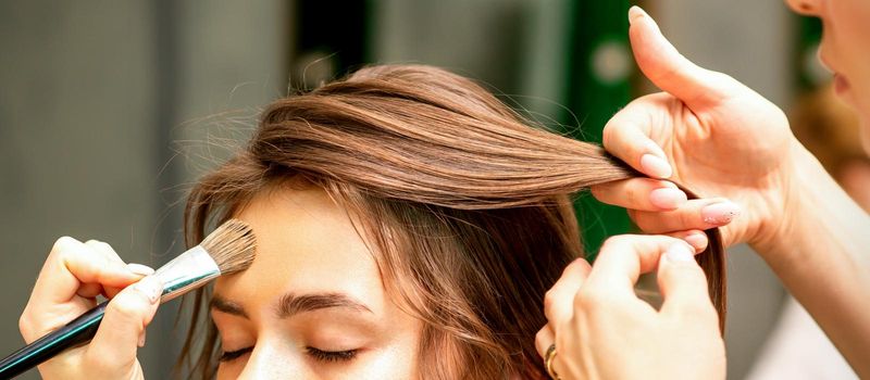 Makeup artist and hairdresser prepare the bride making hairstyle and makeup in a beauty salon