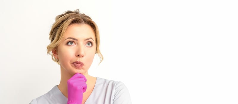 Young caucasian female doctor wearing gloves thoughtful looking away isolated on white background