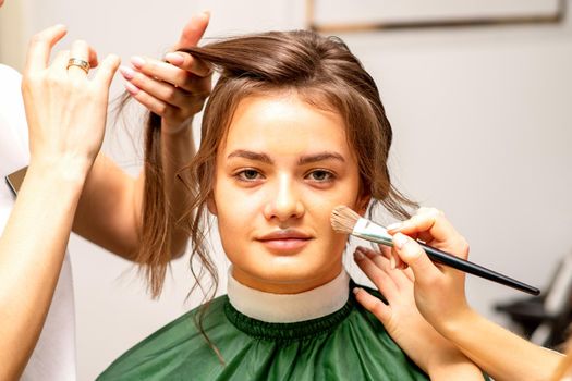 Makeup artist and hairdresser prepare the bride making hairstyle and makeup in a beauty salon