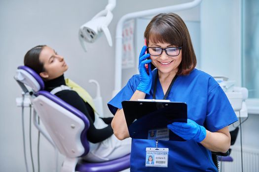 Dentist doctor nurse in the office talking on the phone. Dentistry, hygiene, treatment, medicine, dental health care concept