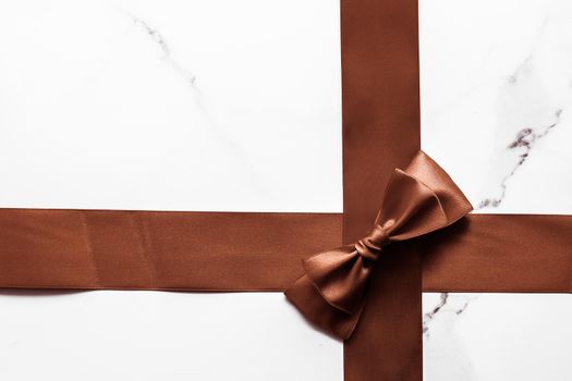 Holiday gift, decoration and sale promotion concept - Chocolate brown silk ribbon on marble background, flatlay