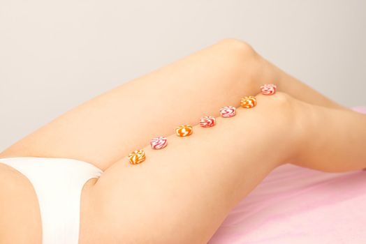 Depilation, waxing concept. Round candies lying down in a row on the female leg, close up