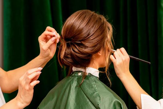 Makeup artist and hairdresser prepare the bride making hairstyle and makeup in a beauty salon