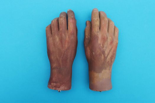 Artificial hands on blue paper background.