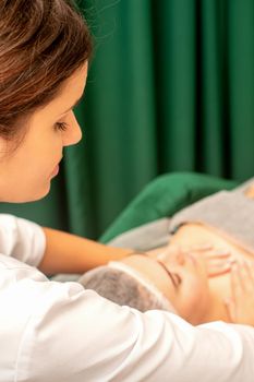 Massaging female breast, and shoulder. Beautician doing chest and shoulders massage of the young beautiful caucasian woman in beauty spa salon