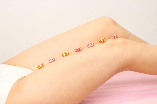 Depilation, waxing concept. Round candies lying down in a row on the female leg, close up