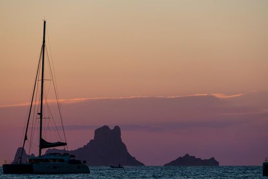 Two sailboats silhouetted by Es Vedra at sunset