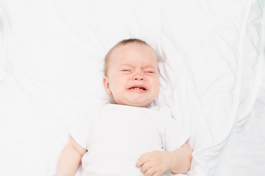 The baby is crying in his crib . The baby 's teeth are teething . Colic in babies . Hungry baby . Baby on a white background