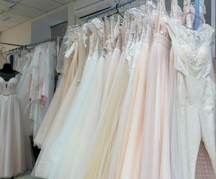 White and cream wedding dresses on a hanger in a bridal boutique. Close up.