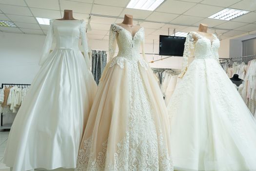 Three chic wedding dresses on mannequins. Three different models of beautiful wedding dresses.