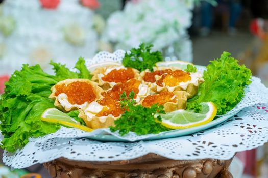 Red caviar and grated cheese in small dough baskets. A delicious cold appetizer with seafood. Close up