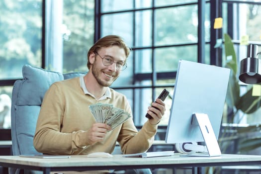 Portrait of successful financial investor, businessman smiling and looking at camera man holding dollars cash and mobile phone working inside modern office.