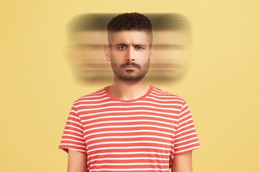 Triple exposure creative portrait of serious handsome bearded man in red t-shirt looking at camera with angry face. Mental health concept. Indoor studio shot isolated on yellow background.