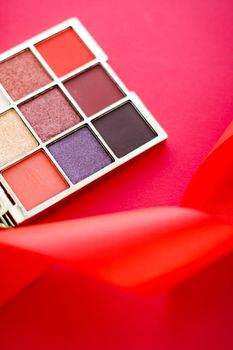 Cosmetic branding, mua and girly concept - Eyeshadow palette and make-up brush on red background, eye shadows cosmetics product for luxury beauty brand promotion and holiday fashion blog design