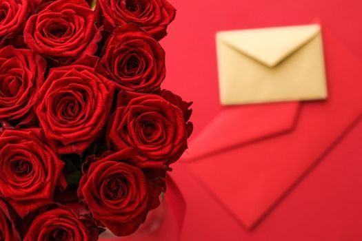 Holiday gift, flowers flatlay and happy relationship concept - Love letter and flower delivery service on Valentines Day, luxury bouquet of red roses and card envelopes on red background