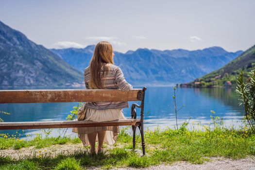 A woman sits on a bench and admires the view of the Bay of Kotor. Montenegro.