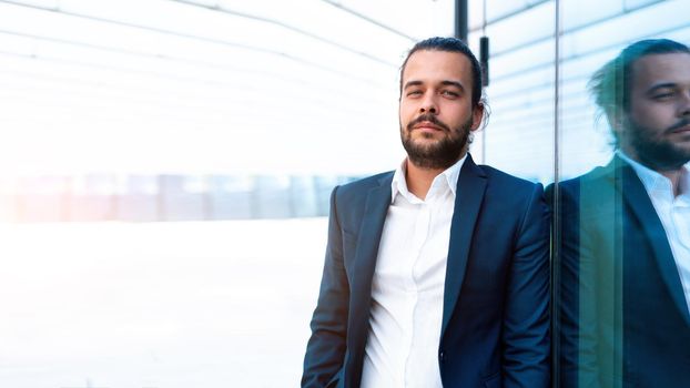 Successful businessman in suit with beard standing near office building confidently looking at camera lean wall. Hispanic male business person portrait. Web banner, Free space. Modern Business people