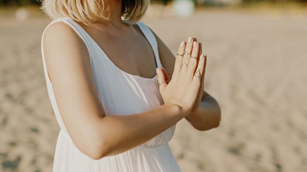 Praying meditating woman, reading mantras, directs thoughts, requests or gratitude to universe. Beach, morning near sea. Spirituality, religion, God concept. High quality photo