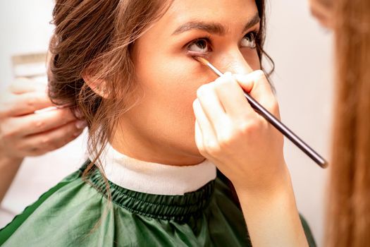 Makeup artist and hairdresser prepare the bride making hairstyle and makeup in a beauty salon