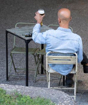 Rear view of a man enjoying a glass of beer on a table in Madrid city center.