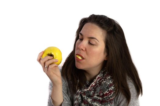 young brunette girl eating an apple on a white background with copy space