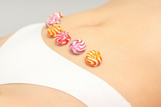 Concept of intimate depilation, intimate waxing, depilation. Round candies lying down in a row on the female bikini zone, intimate area, close up