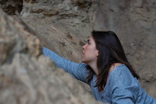 young girl learning rock climbing in high mountain with blue sweater, black tights and boots.