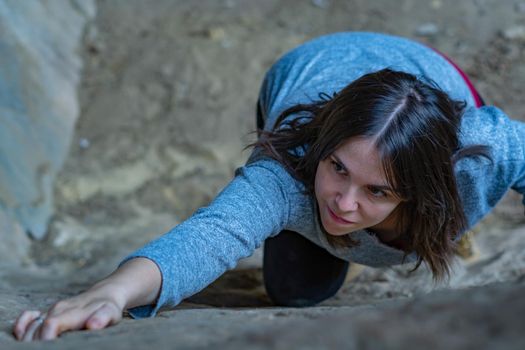 young girl learning rock climbing in high mountain with blue sweater, black tights and boots.