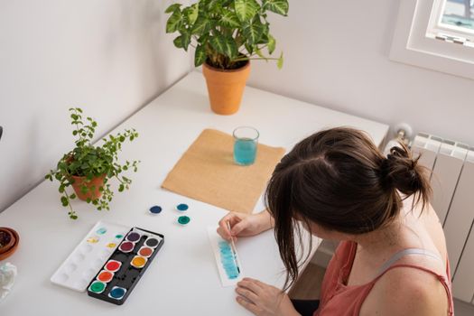 woman painting with watercolors in her studio at home