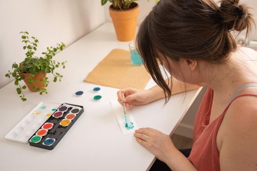 woman painting with watercolors in her studio at home