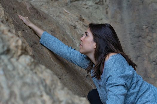 young girl learning rock climbing in high mountain with blue sweater, black tights and boots.