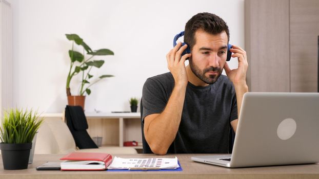 Man listening music with his headphones at the office. Good vibe