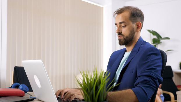 Freelancer businessman working on the laptop computer in the house and his wife is in the background