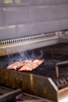 Delicious smoked bacon on grill in kitchen restaurant. Food preparation