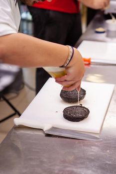 Chef seasoning burger bun in kitchen restaurant