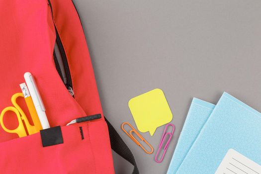 Back to school concept. School backpack with educational supplies on a grey background. Top view. Flat lay student desk.