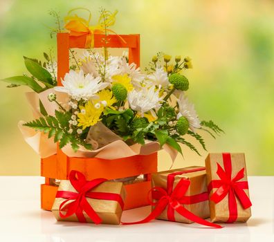 Beautiful bouquet of yellow and white flowers in the wooden basket with gift boxes.