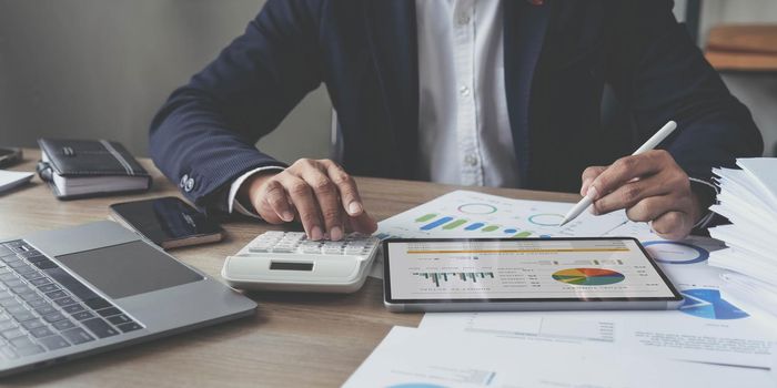 businessman writing business plan at desk in modern office. Planning analyze investment, business strategy and marketing, using graph chart and digital tablet..