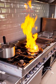 Chef making flambe fois gras in restaurant kitchen