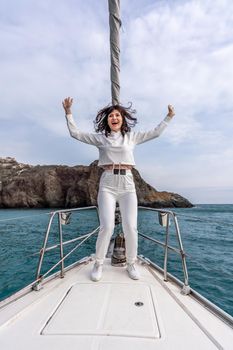 Woman standing on the nose of the yacht at a sunny summer day, breeze developing hair, beautiful sea on background.