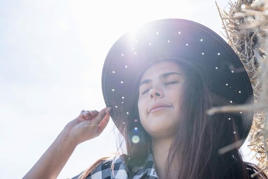 Beautiful girl on straw bales. beautiful woman in plaid shirt and cowboy hat resting on haystack