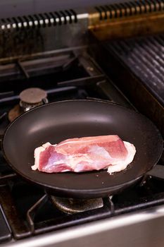 Chef fries duck breast on pan in restaurant kitchen