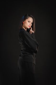 30 year old brunette woman in a black sleepwear on a black background.